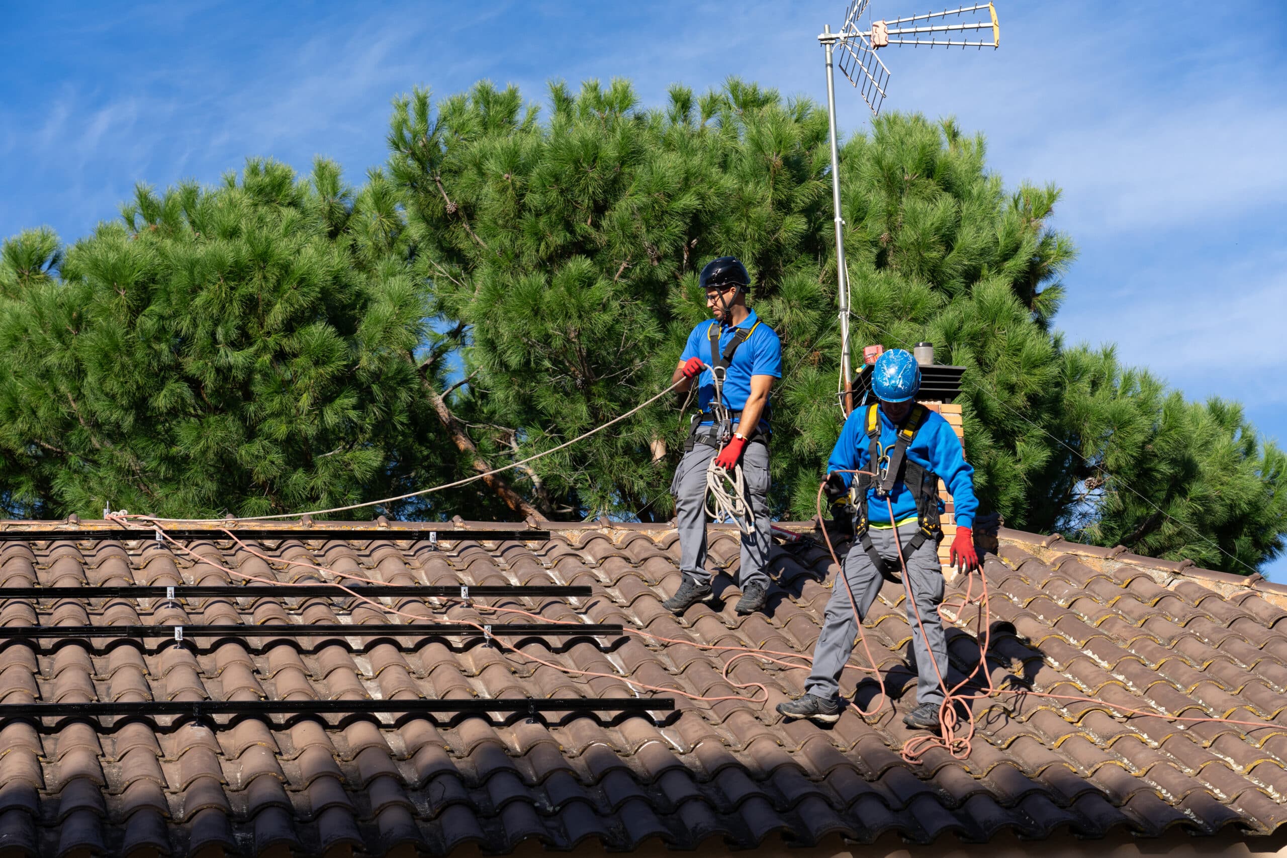 Two men installing solar panels on a house