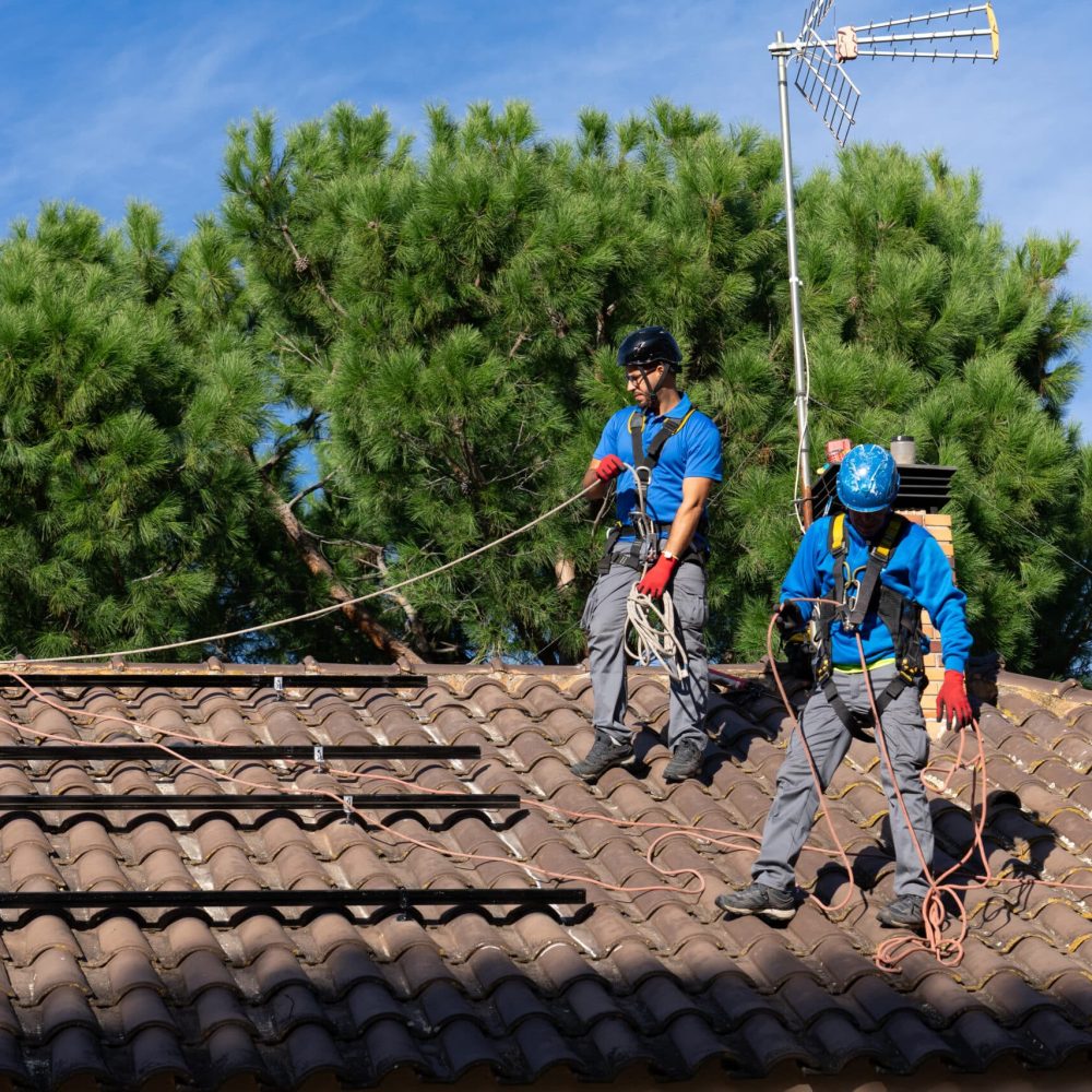 Two men installing solar panels on a house